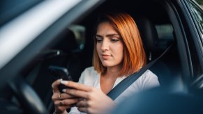 A female driver scrolling on her cell phone