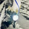 A snow-covered car in Wisconsin with the left headlamp broken and a flashlight strapped in to replace it, shown in very close view
