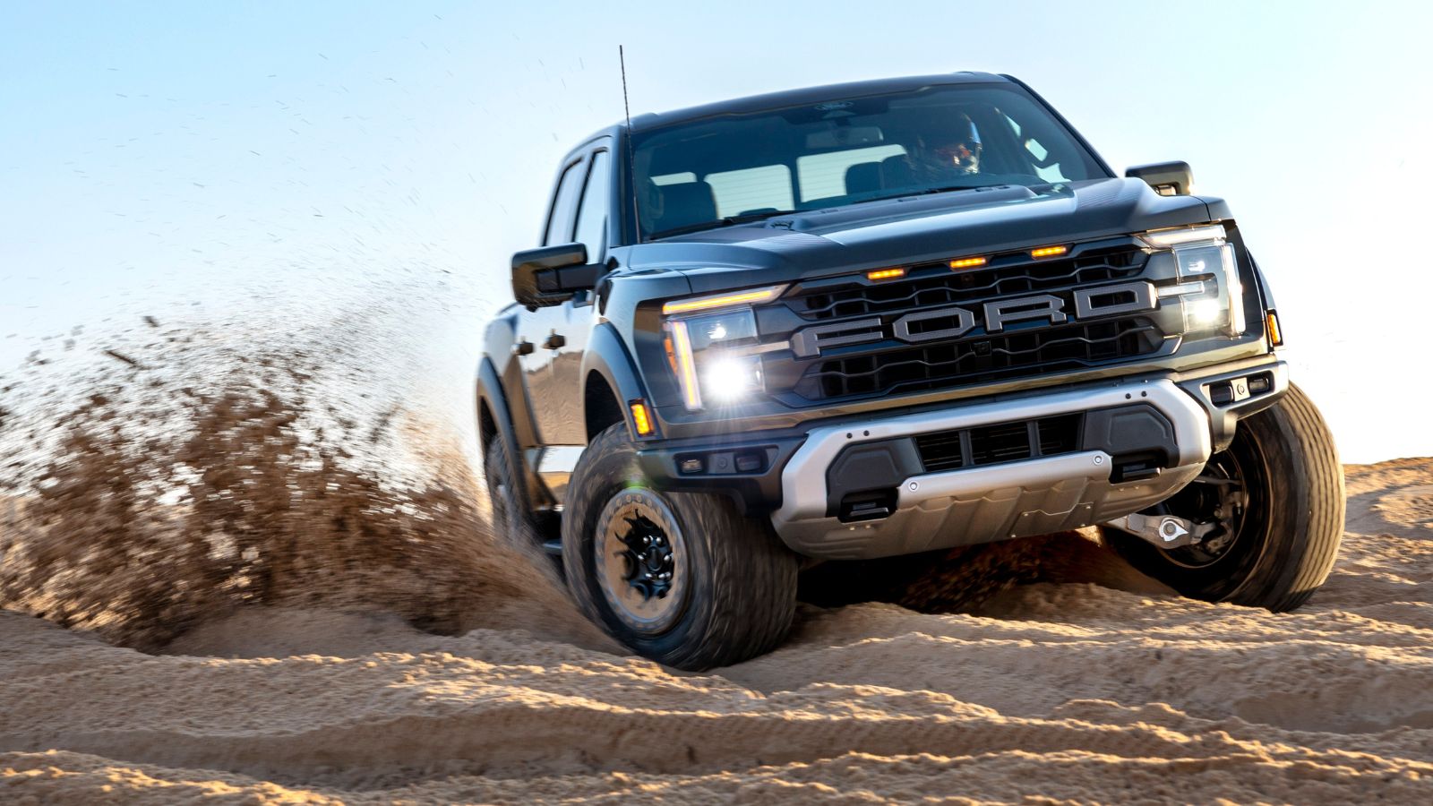 A Ford F-150 Raptor off-roading on sand in right front angle view