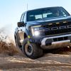 A Ford F-150 Raptor off-roading on sand in right front angle view