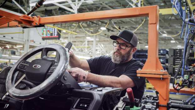 Ford factory worker with hands on an F-150 Lightning steering column