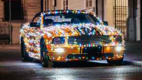 A yellow Ford Mustang covered in Christmas light strings