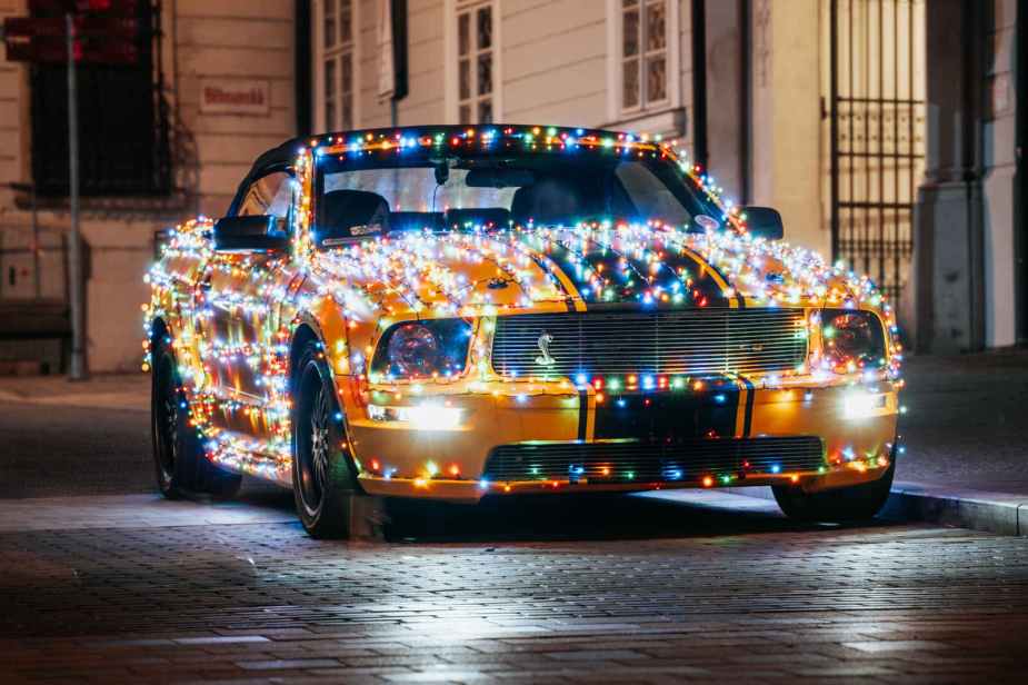 A yellow Ford Mustang covered in Christmas light strings