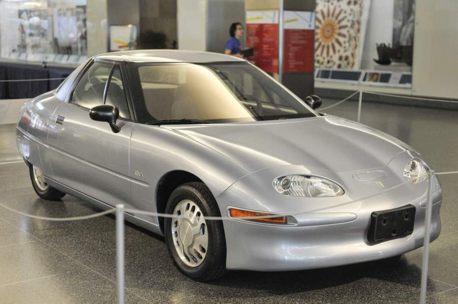 A silver GM EV1 electric car, produced from 1996-1999, parked in a museum in right front angle view
