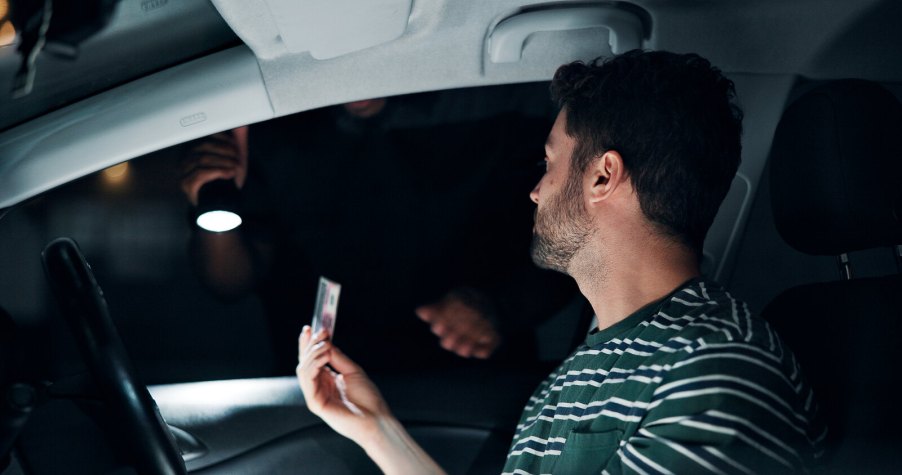 A driver hands a police officer their license at night