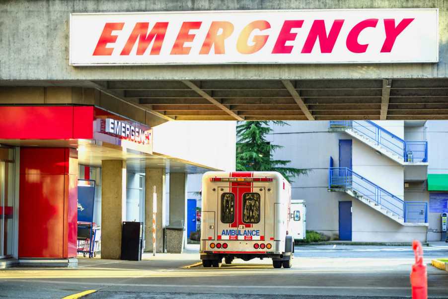 A hospital's emergency department entrance with ambulance parked outside