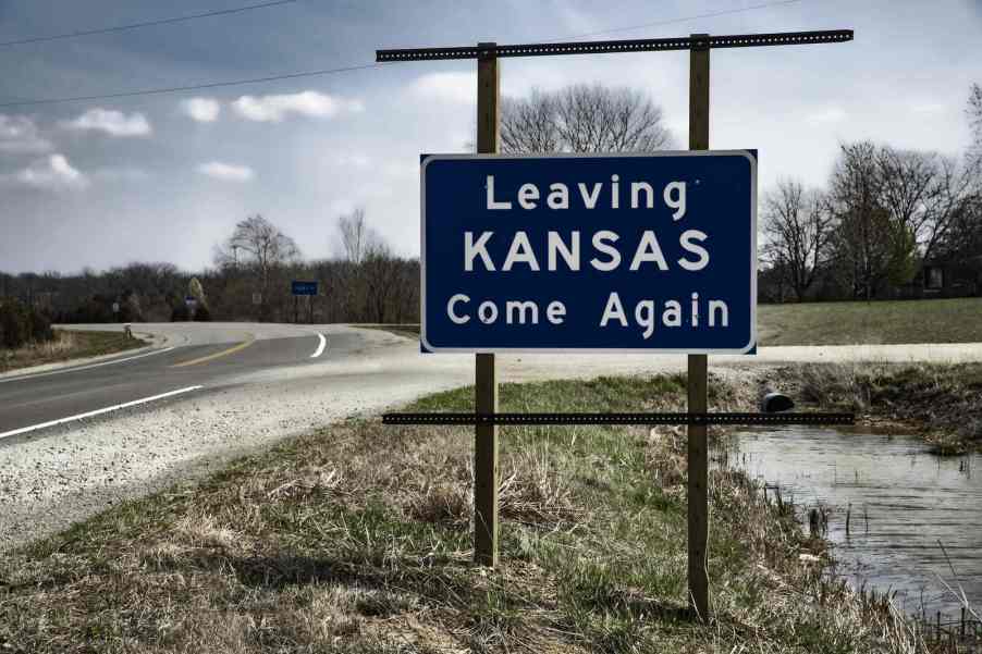 A road sign reading "Leaving Kansas Come Again"