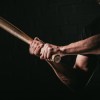 A man holding a baseball bat ready to swing with shadowed black background