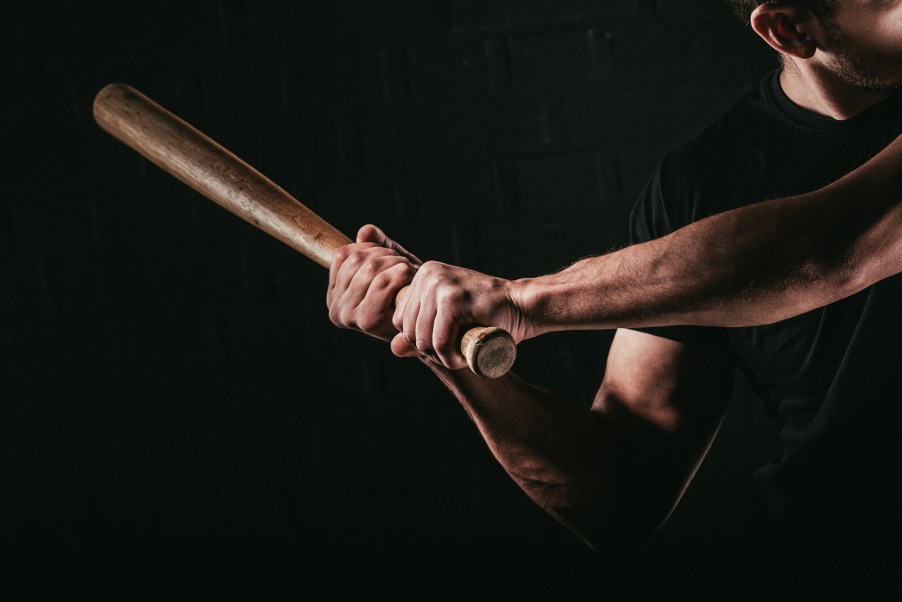 A man holding a baseball bat ready to swing with shadowed black background