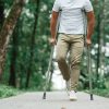 A man standing with crutches on a wooded paved path
