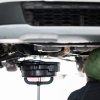 A mechanic drains car oil facing away from viewer