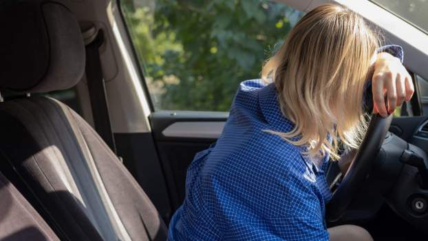 A blonde woman driver slumped over her steering wheel DUI depiction