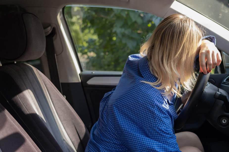 A blonde woman driver slumped over her steering wheel DUI depiction