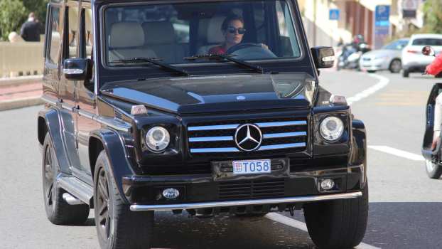 A woman driving a black Mercedes-Benz G-Wagon