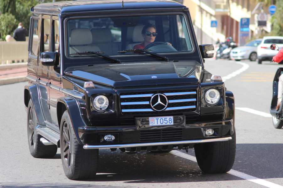 A woman driving a black Mercedes-Benz G-Wagon
