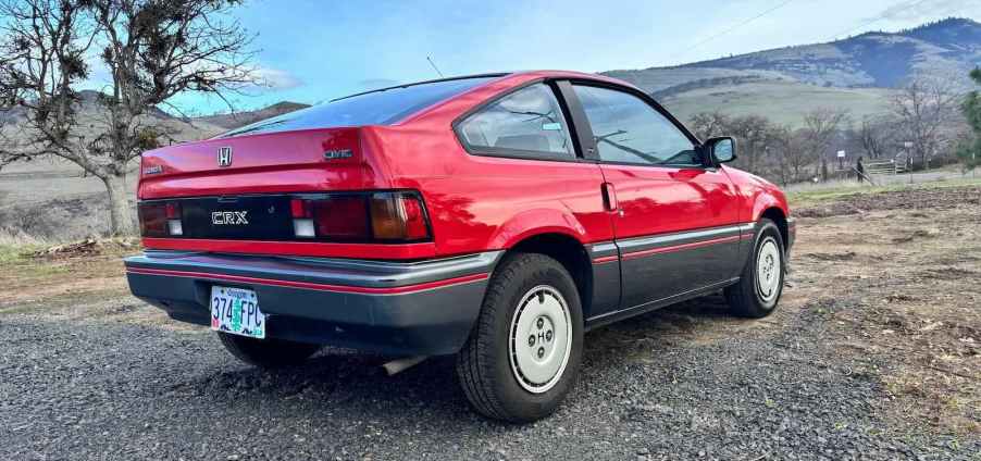 Kammtail rear of a red Honda CRX compact car, with mountains visible in the background.