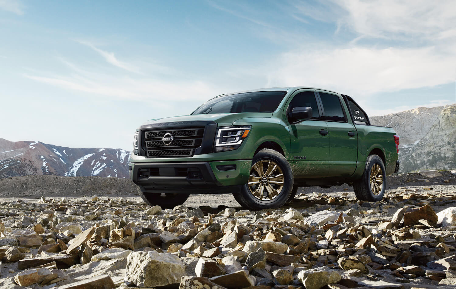 Nissan Titan pickup truck parked on rocks, mountains visible in the background.