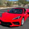 Bright red Corvette in a parking lot, the desert and cactuses visible in the background.