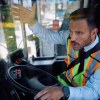 Angry bus driver gestures with one hand while steering with the other.