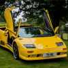 Bright yellow Lamborghini Diablo supercar with its doors up, parked on a grass field.