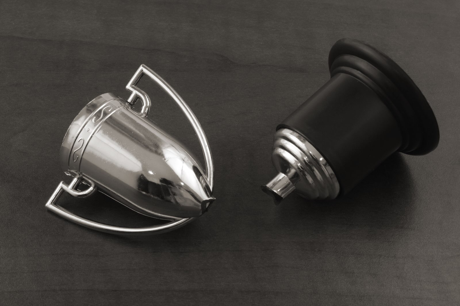 Broken silver trophy on a gray background.
