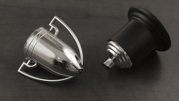 Broken silver trophy on a gray background.