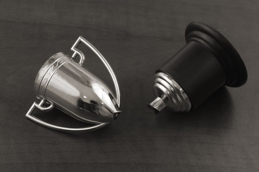 Broken silver trophy on a gray background.