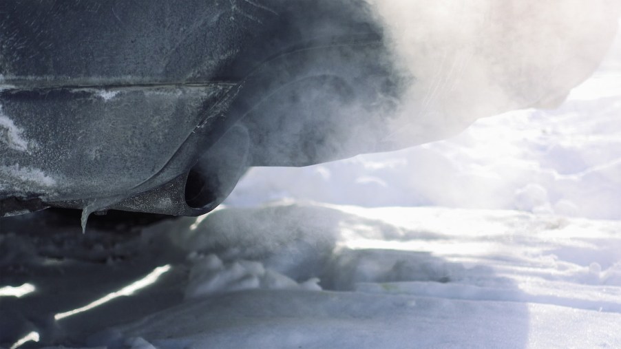 Exhaust from the snowy tailpipe of a car idling early in the morning.