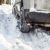 The wheels of a car stuck in a snowbank during the winter.