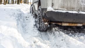 The wheels of a car stuck in a snowbank during the winter.