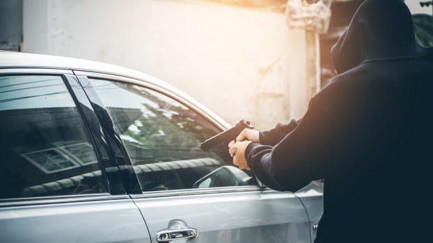 An armed man stealing a car