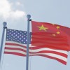 The national flags of China (Front) and USA (rear) wave against the blue sky, white clouds in the background.
