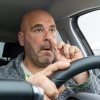 Man picks his nose while driving his car.