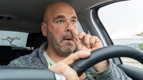 Man picks his nose while driving his car.