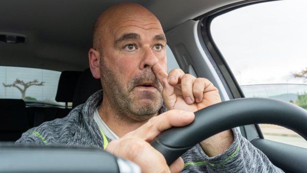 Man picks his nose while driving his car.