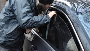 Man forces his way into a truck to steal a hat, his hand on the open window.