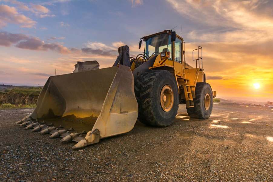 Front loader construction equipment parked in a sand pit, the sunsetting in the background.