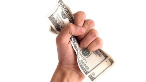 Fist grabbing hundred dollar bills on a white background.