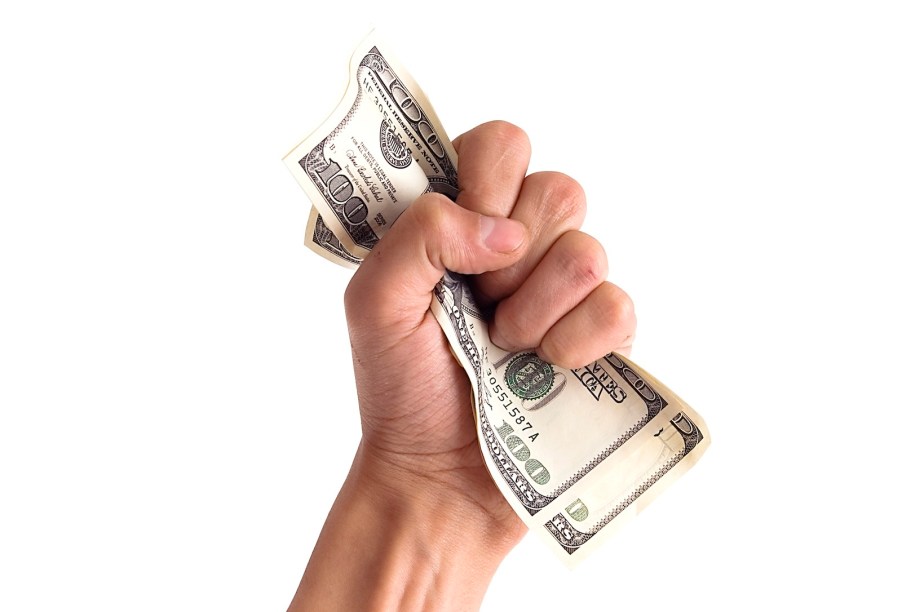 Fist grabbing hundred dollar bills on a white background.