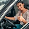 Young woman gives a thumbs up from the driver's seat of her reliable used car.
