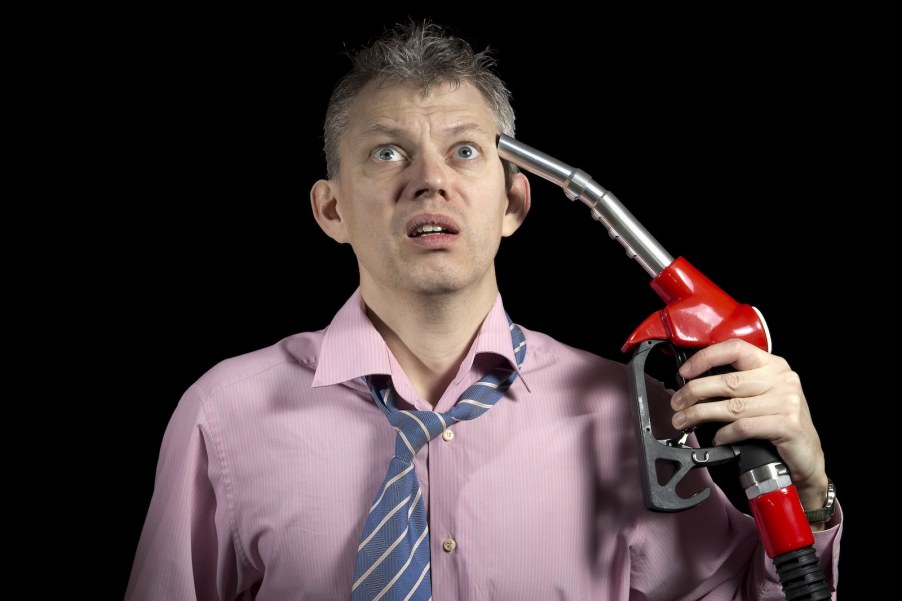 Upset man holds fuel pump nozzle to his head
