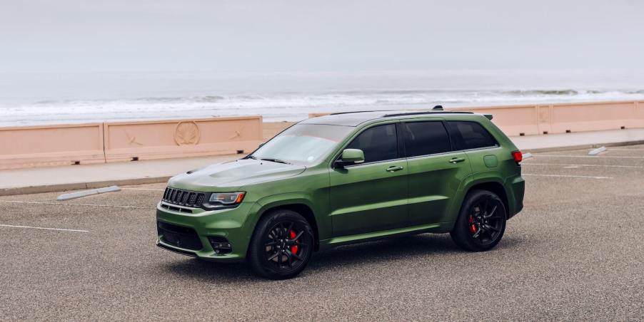 Green Jeep parked in front of the ocean.