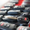 Rows of car keys and fobs on a red background.