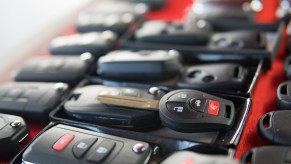 Rows of car keys and fobs on a red background.