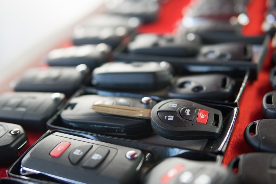 Rows of car keys and fobs on a red background.
