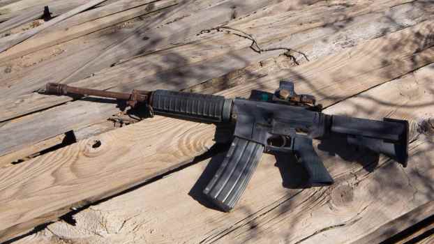 Rusty, lost M16 rifle sitting on a wood deck.