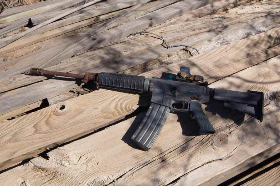Rusty, lost M16 rifle sitting on a wood deck.