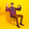 Friendly man smiles and waves, while holding a steering wheel in a regular chair