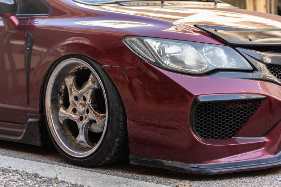 Red Honda Civic on aftermarket wheels parked on the street.