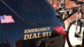 "Emergency Dial 911" sticker on the side of a black police patrol car